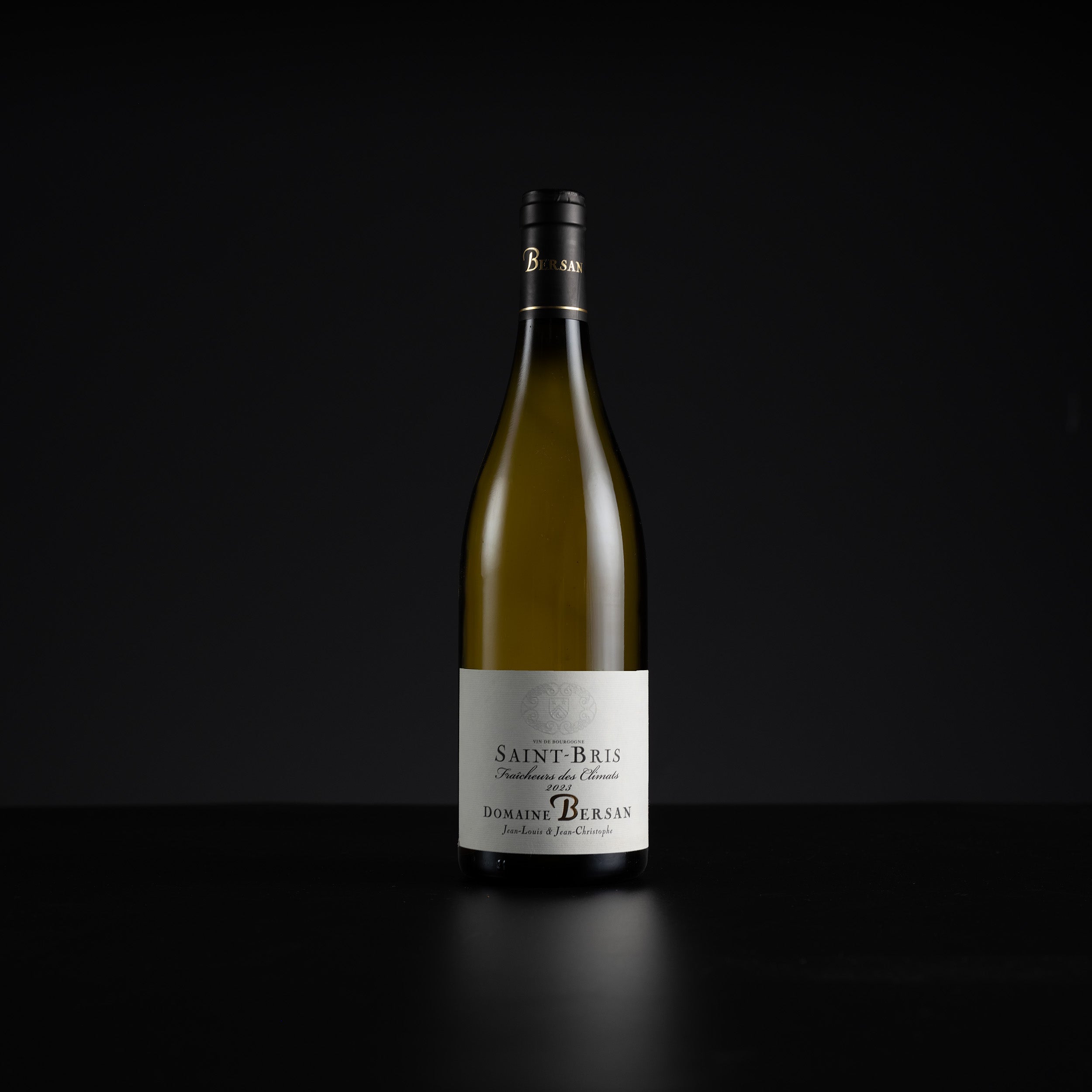 A single bottle of Domaine de Burgan Saint-Bris non-alcoholic white wine, standing upright on a dark reflective surface against a solid black background.