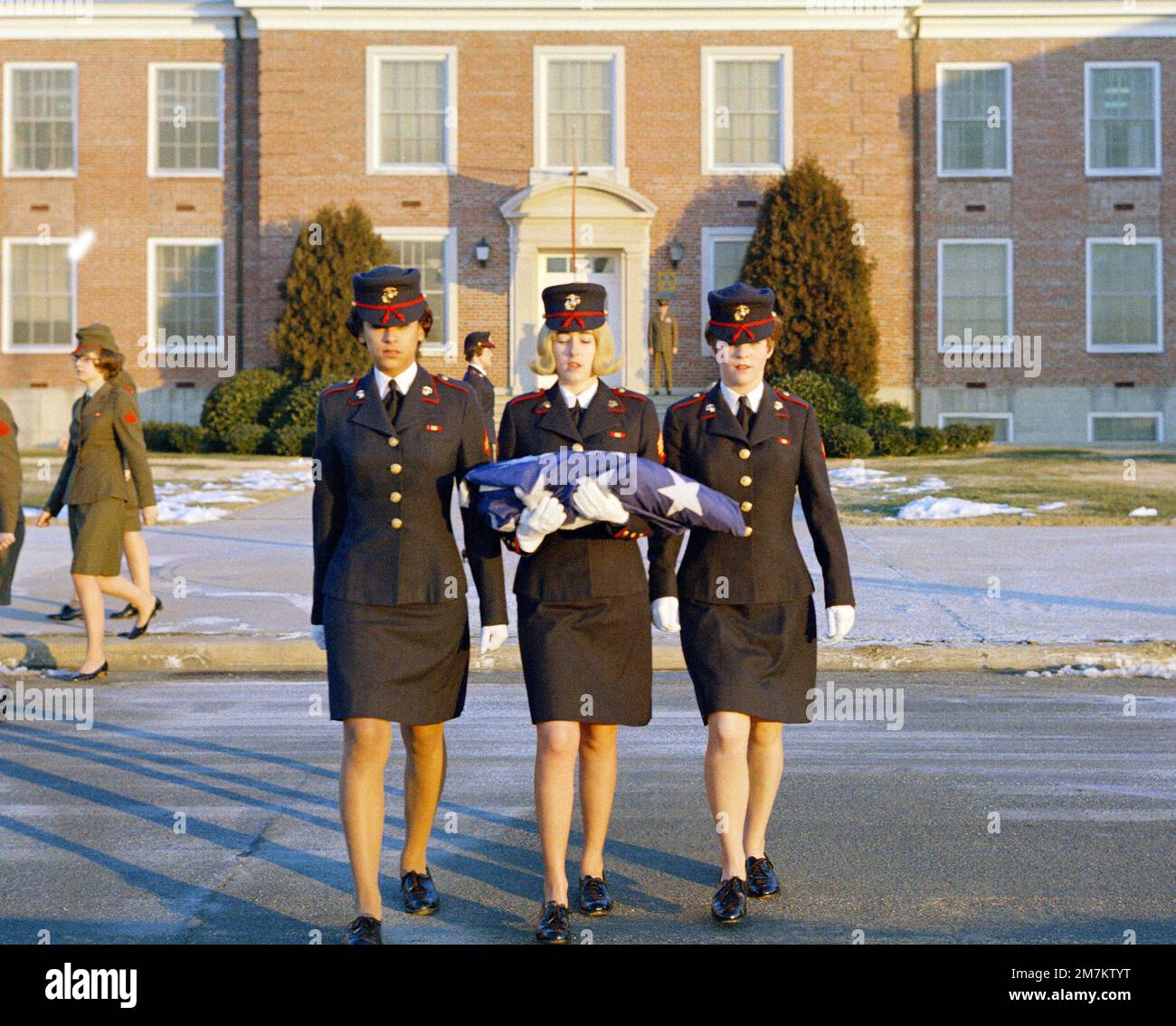 Three female Marines, in dress blue uniforms, raise the morning colors. First view in a series of three. Base: Marine Corps Base, Quantico State: Virginia (VA) Country: United States Of America (USA